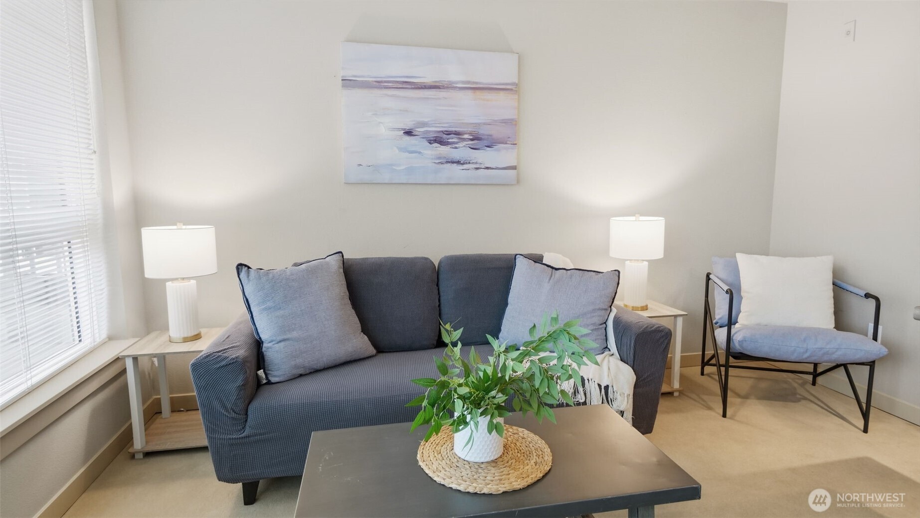 Staged living room with a blue-gray sofa, accent chair, and large window.
