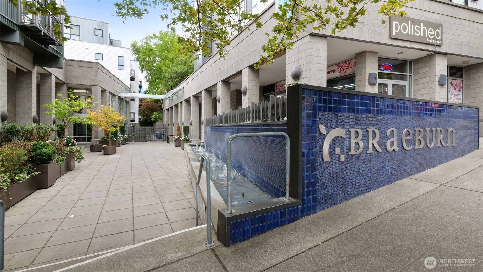 Condominium courtyard with a blue-tiled G.BRÆBURN sign and a narrow water feature.
