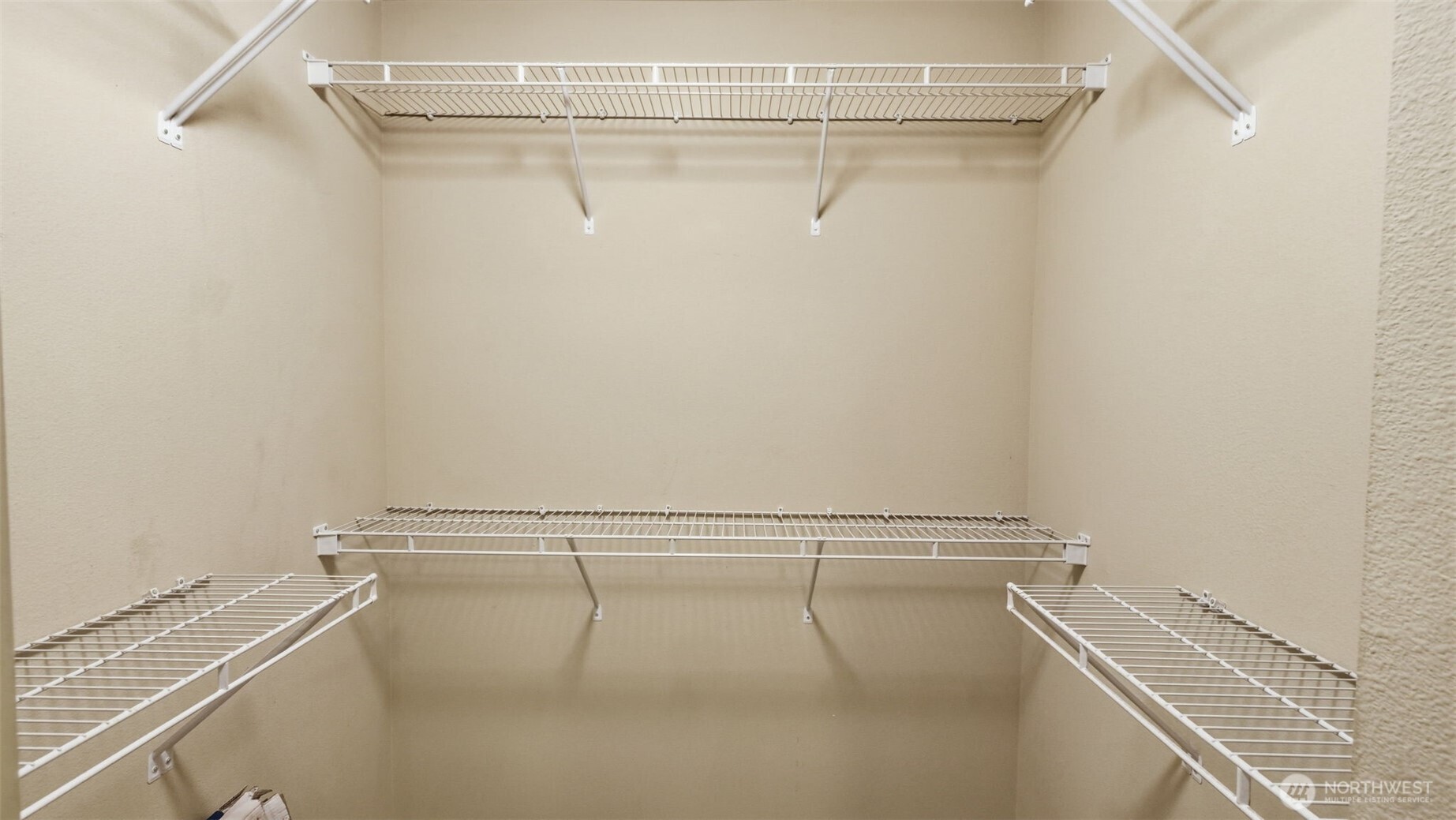 Empty walk-in closet with white wire shelving along three walls.