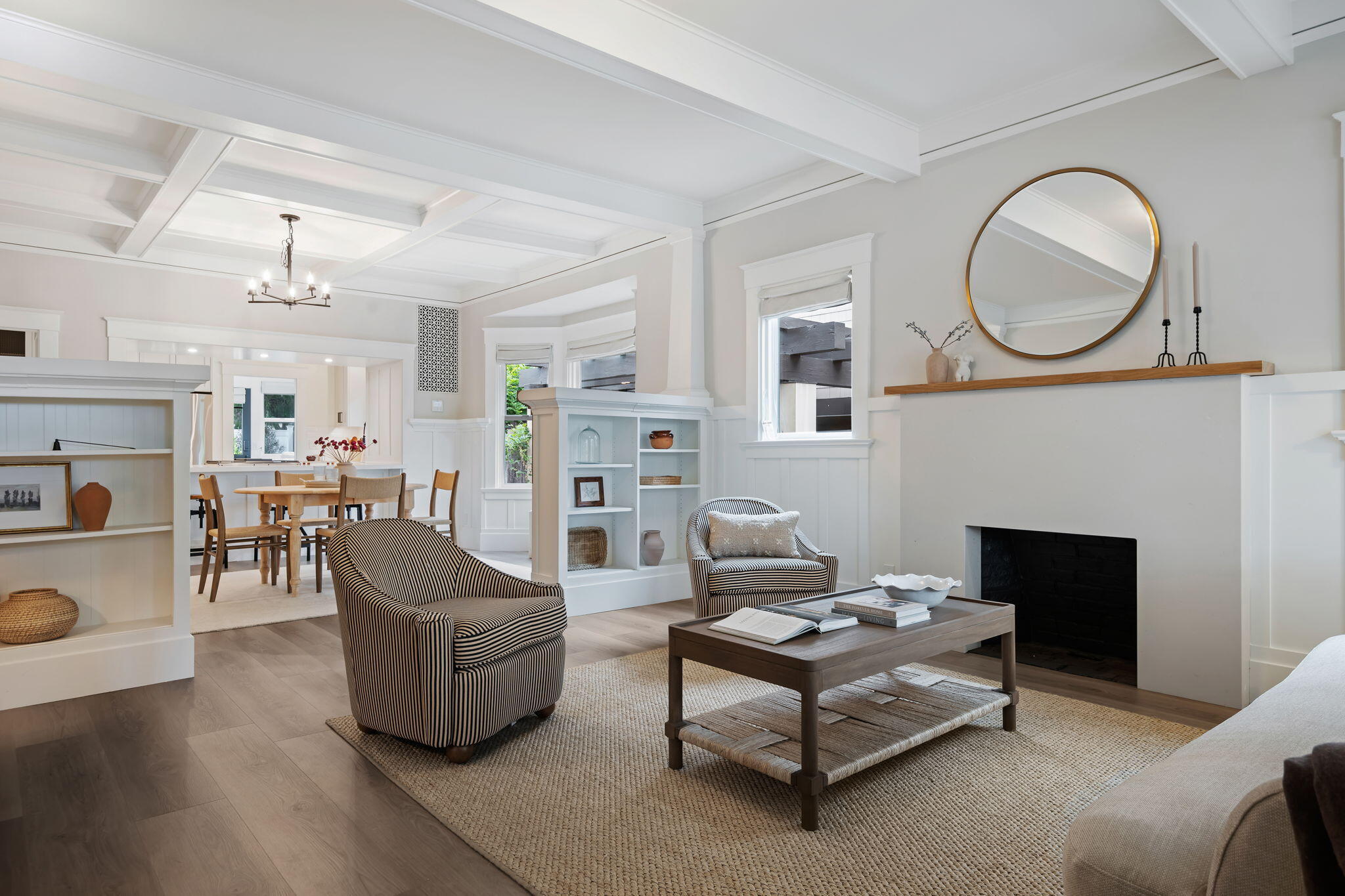 Living room with a coffered ceiling, white fireplace, built-in shelves, and adjoining dining area.