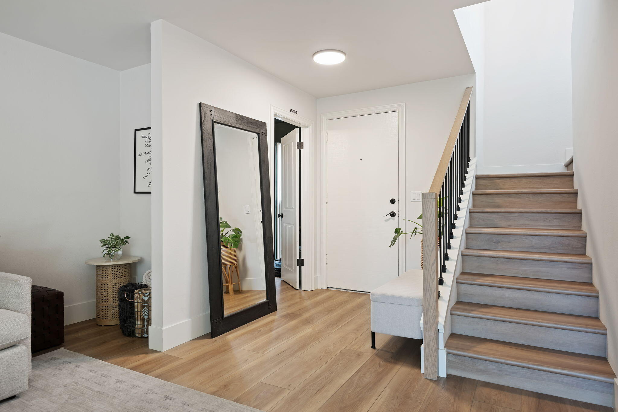 Entry foyer with a wide gray wood staircase, black balusters, and a large dark-framed mirror.
