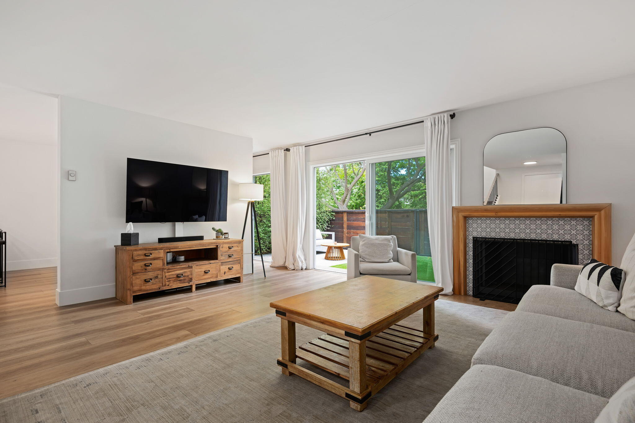 Staged living room with a tiled fireplace and sliding doors to a fenced patio.
