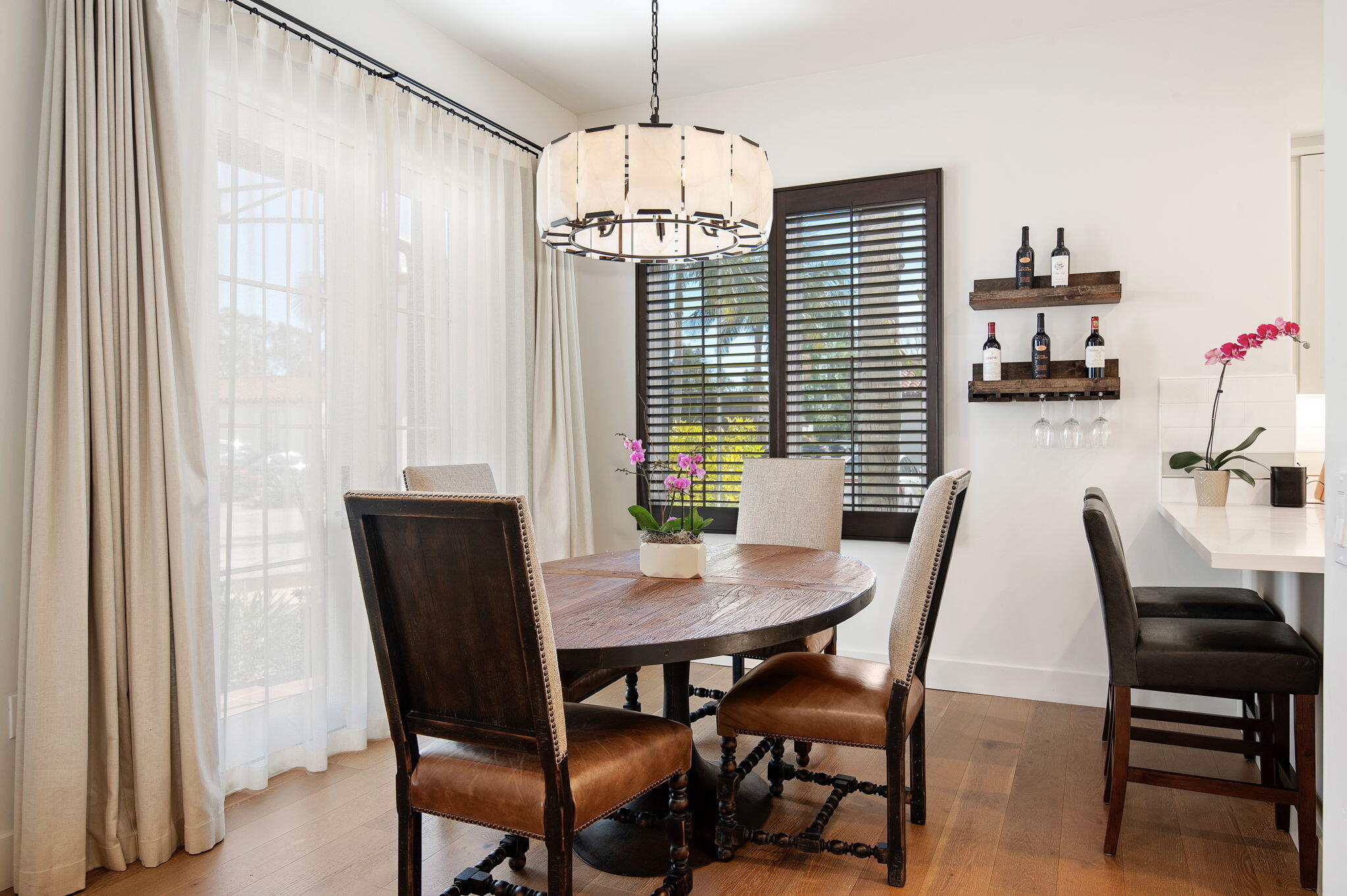 Dining area with a round wood table, upholstered chairs, and a large pendant light.