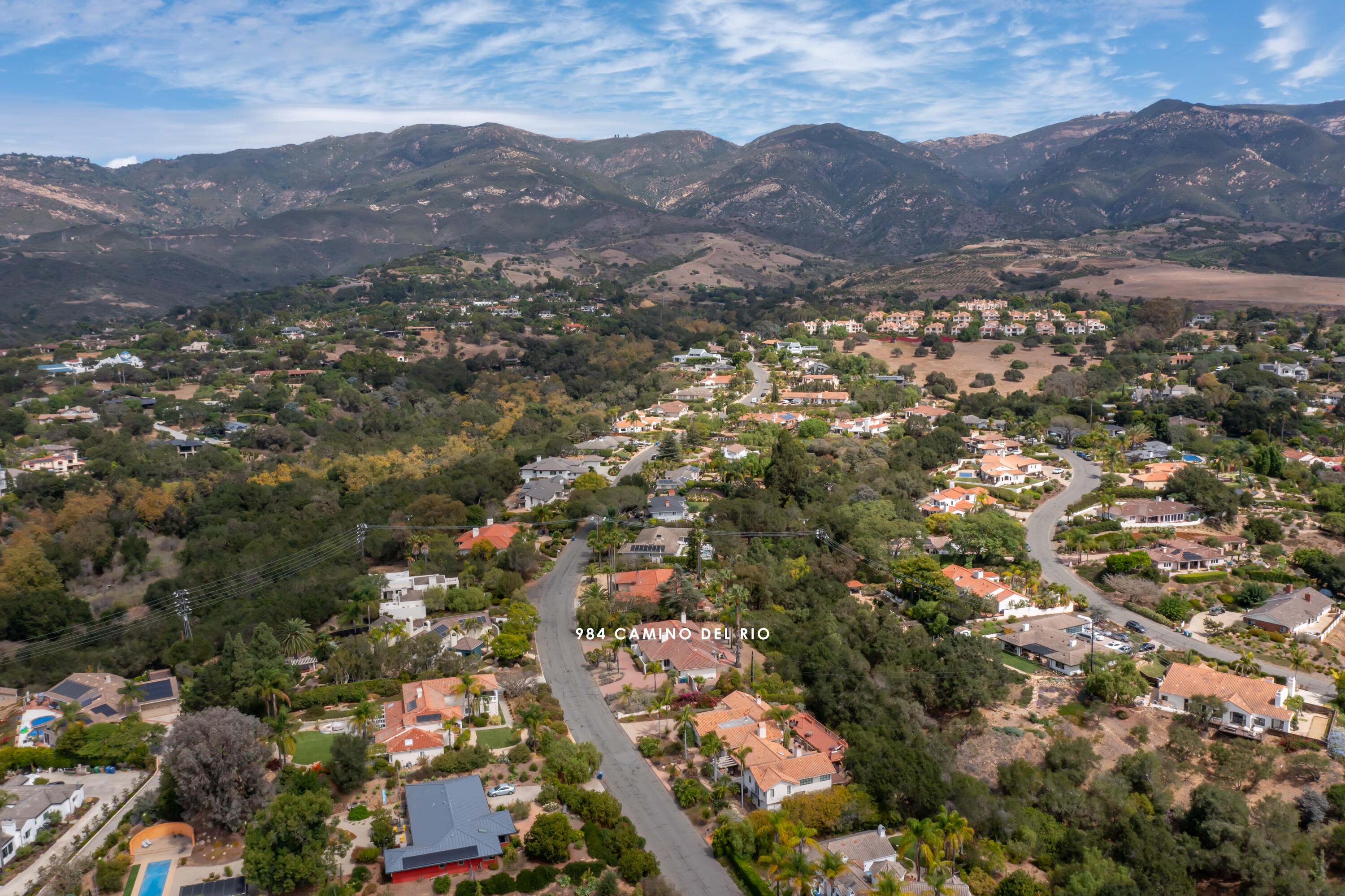 Aerial view of a residential neighborhood with winding streets and mountain foothills beyond.