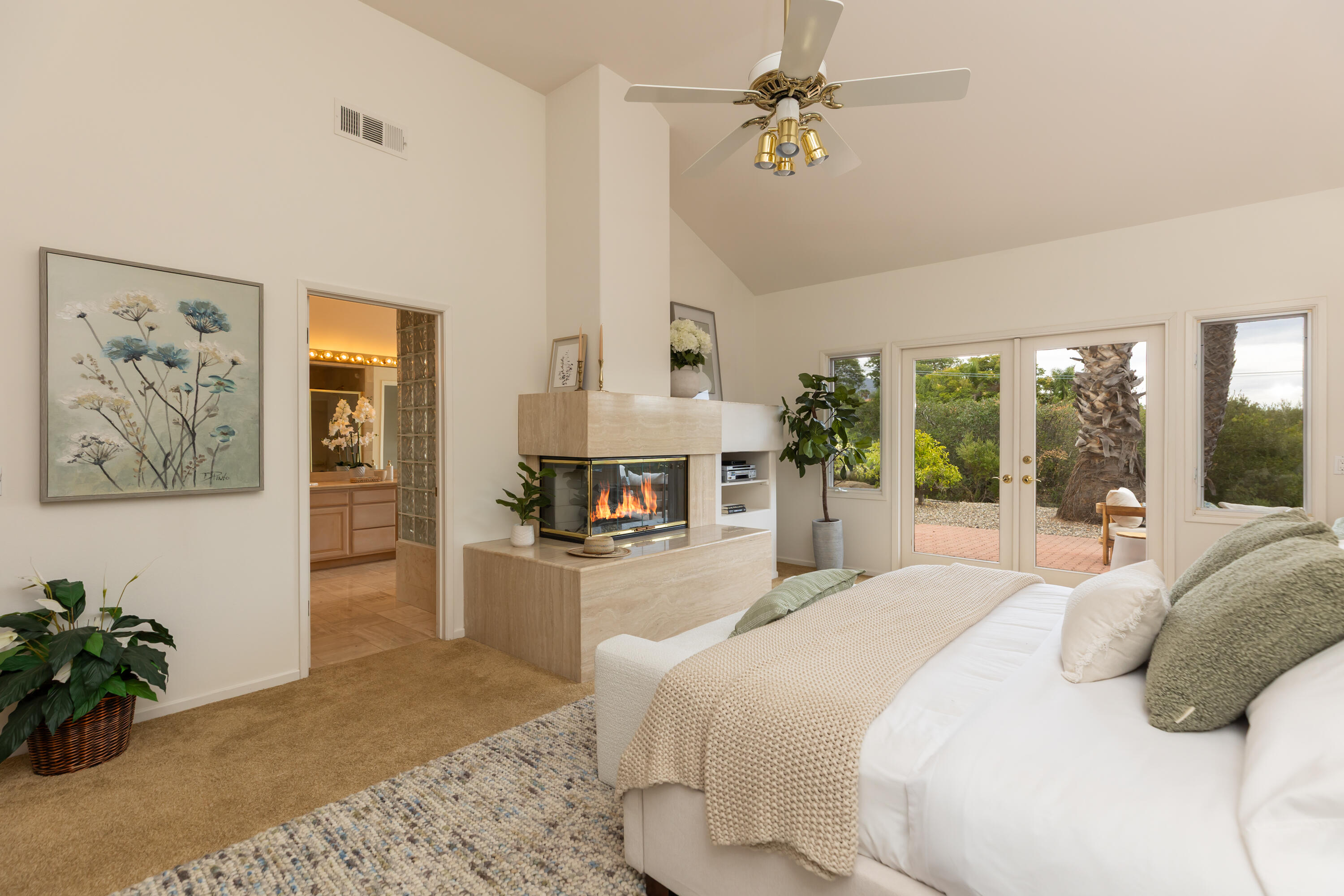 Living room with a stone fireplace, vaulted ceiling, and glass doors to a garden.