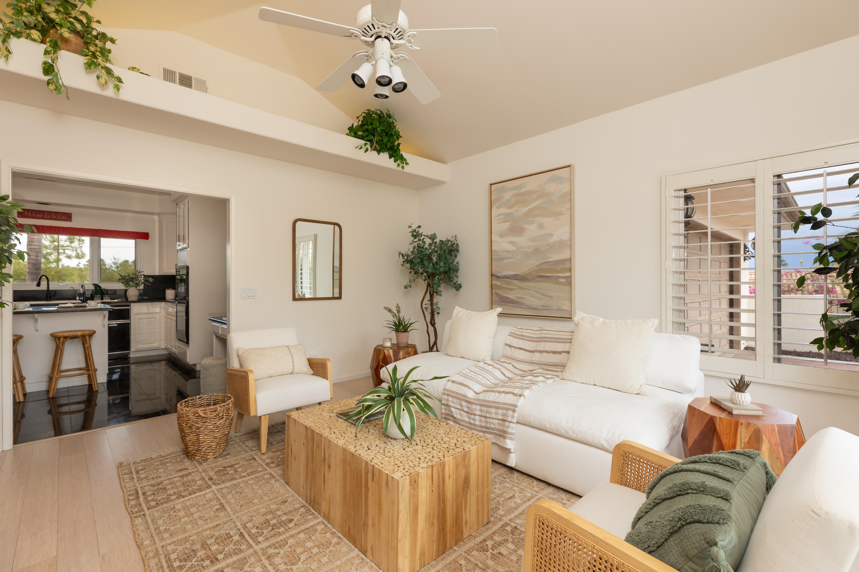 Bright living room with a white sectional, woven coffee table, and open view into the kitchen.