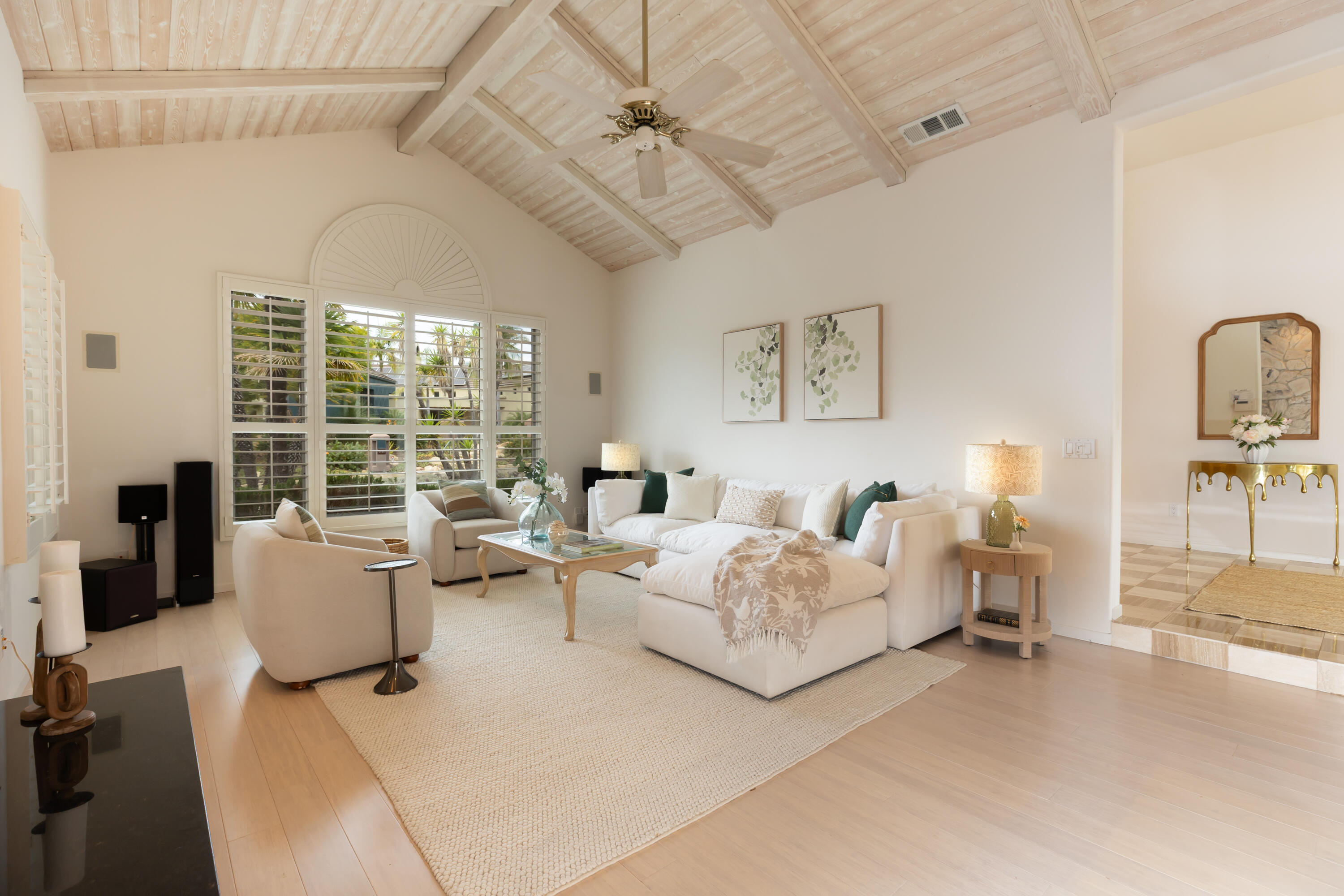 Living room with white seating, shuttered garden-facing windows, and a vaulted wood-beam ceiling.