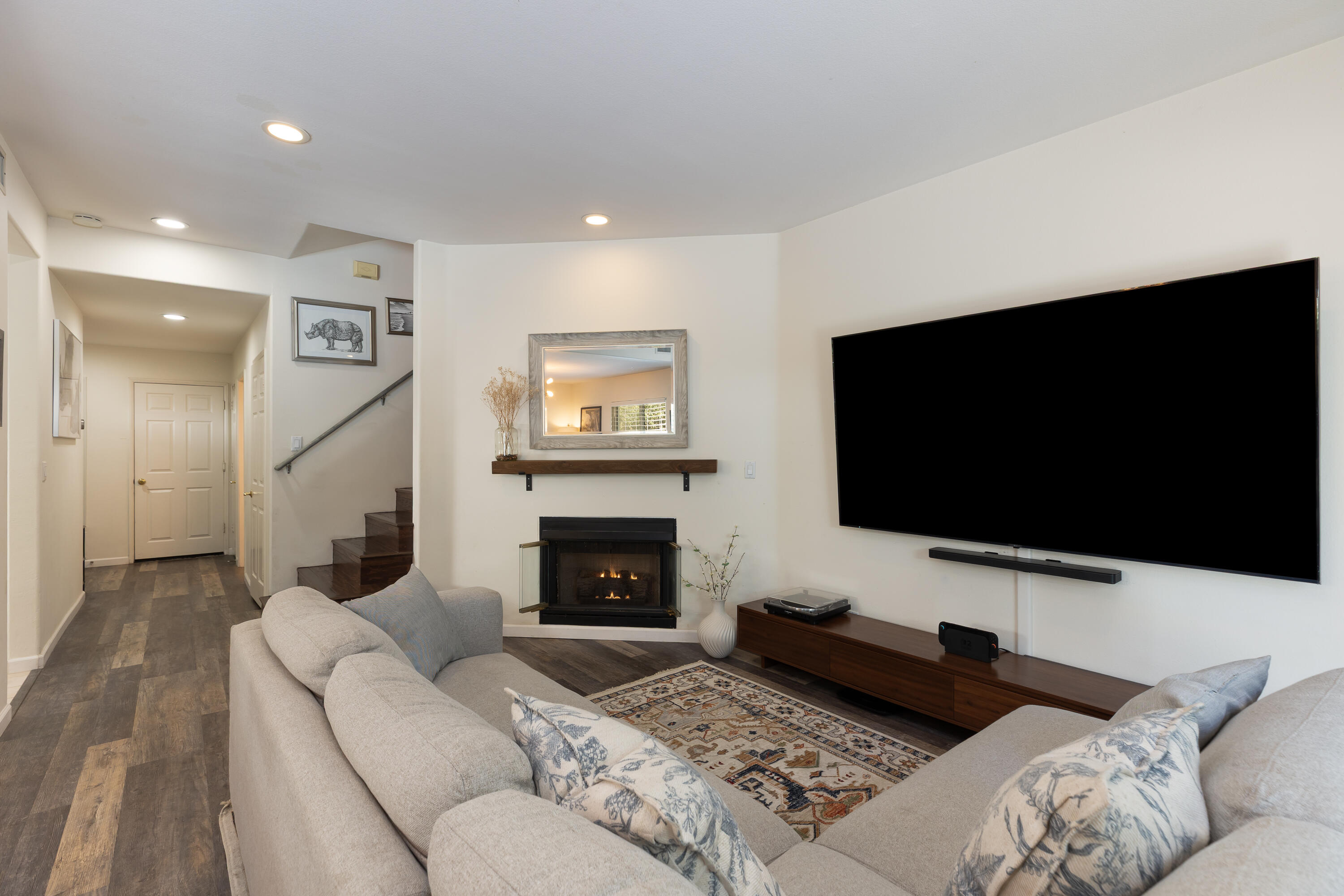 Living room with a large television, gas fireplace, and light sectional sofa.
