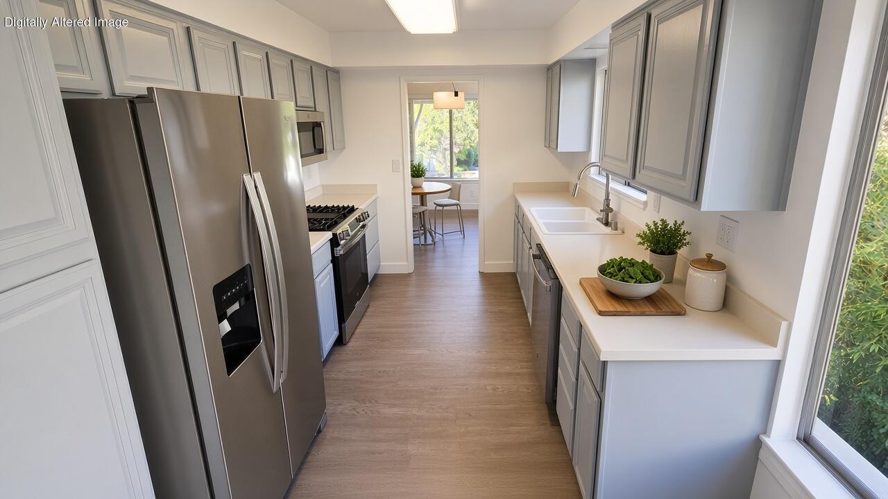 Galley kitchen with gray cabinets, stainless steel appliances, white counters, and a breakfast nook.