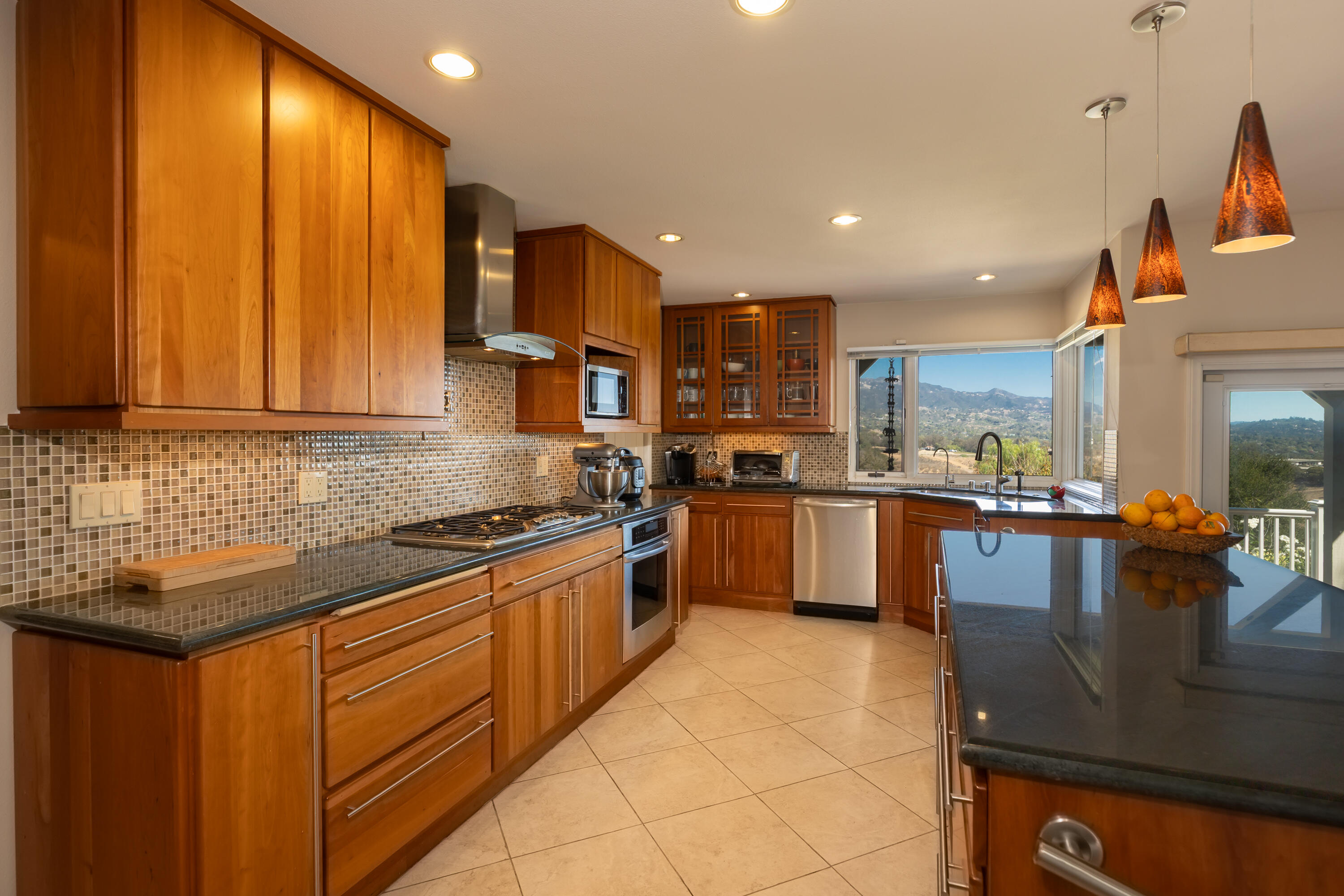 Kitchen with warm wood cabinets, a large dark island, stainless appliances, and mountain views through the windows.