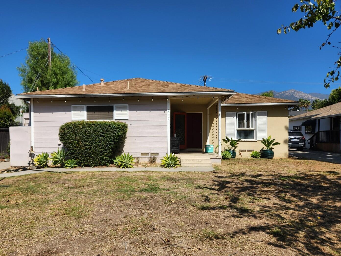 Single-story home with a covered entry, drought-tolerant landscaping, and mountains behind it.