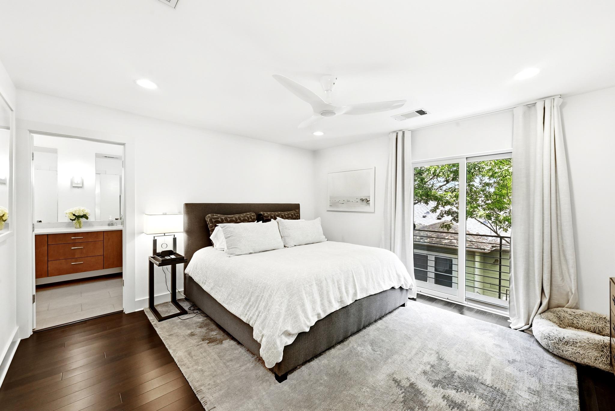 Bedroom with white bedding, a dark headboard, and sliding glass doors to a balcony.