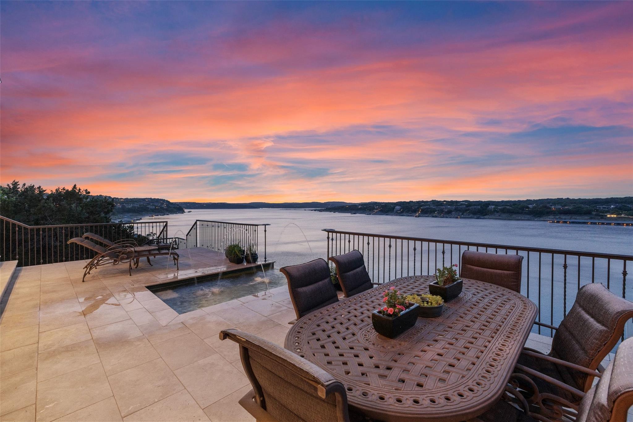 Stone terrace with outdoor dining and a plunge pool overlooking the lake at sunset.