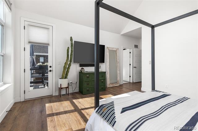 Bedroom with a black canopy bed frame, green dresser, and glass door to an outdoor seating area.