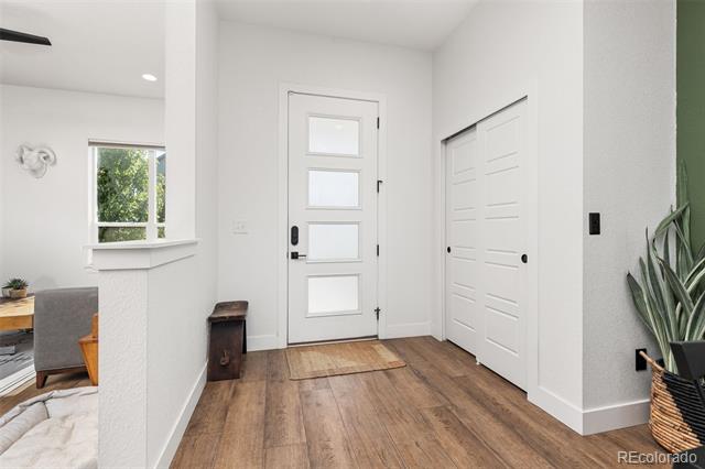 Bright entryway with a frosted-panel front door, double closet, and warm wood flooring.