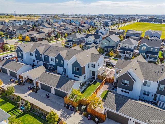 Aerial view of modern Denver homes, fenced yards, and a broad grassy field.