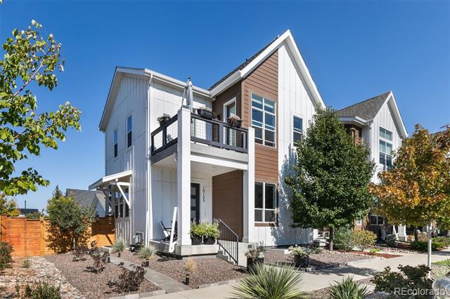 Modern two-story home with a balcony, white siding, and drought-tolerant landscaping.