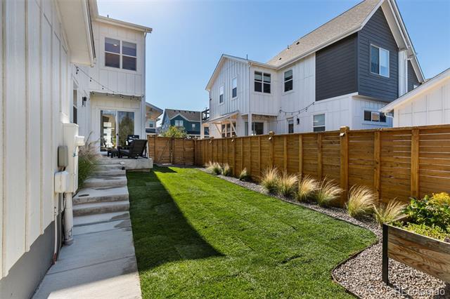 Fenced backyard with a green lawn, concrete patio steps, and wooden privacy fence.
