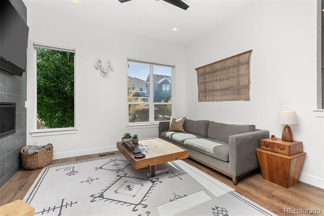 Living room with a gray sectional, wood coffee table, patterned rug, and dark tiled fireplace wall.