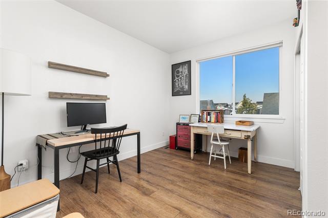 Home office with two desks, a black chair, and a large window.
