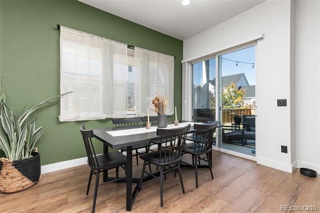 Dining room with a black table, green accent wall, and sliding glass doors to a balcony.