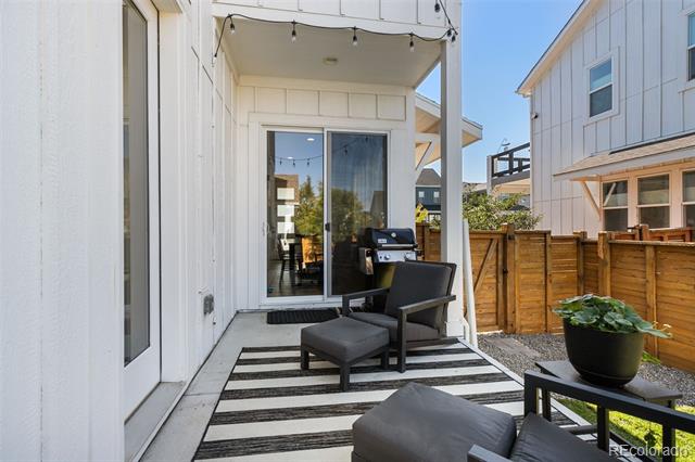 Patio with dark lounge chairs on a striped rug beside sliding glass doors and a wooden privacy fence.