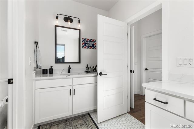White bathroom with double-sink vanity, black fixtures, and an open paneled door.