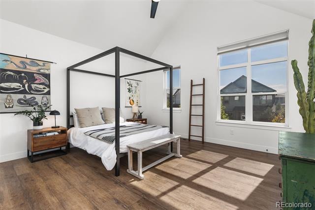 Bedroom with a black four-poster bed, wood floors, and a large sunlit window.