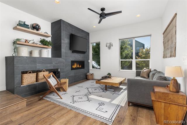 Living room with a charcoal tiled fireplace wall, gray sectional, patterned rug, and large windows.