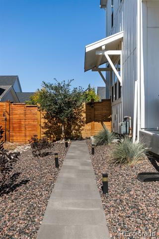 Side yard with a concrete walkway, gravel landscaping, and a wooden privacy fence.