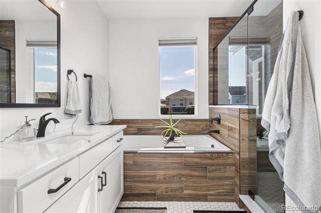 Modern bathroom with a double vanity, wood-paneled soaking tub, and glass shower.