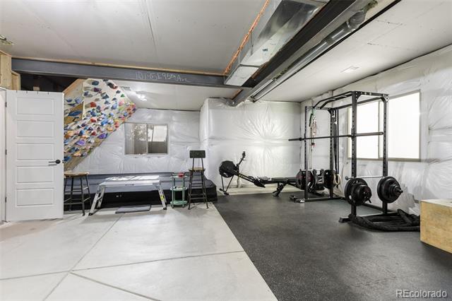 Basement gym with a climbing wall, weight rack, and rubber flooring.