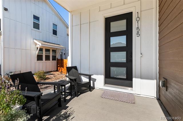 Front entry with a black glass-panel door and black patio seating on the covered porch.