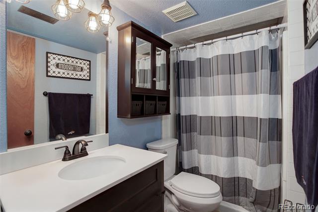 Bathroom with a white vanity, dark wood cabinetry, and a gray-and-white striped shower curtain.