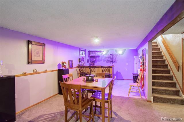Basement dining area with a wooden table, purple accent lighting, and a staircase.