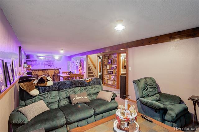 Living room with a green sectional, recliner, built-in bookshelves, and purple accent lighting.