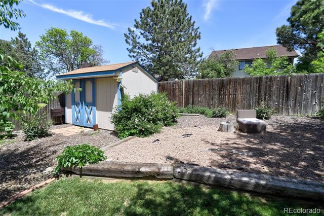 Backyard with a blue-trimmed storage shed, wooden privacy fence, and gravel landscaping.