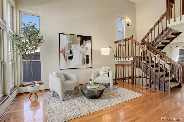 Living room with armchairs, large windows, and a prominent wooden staircase.
