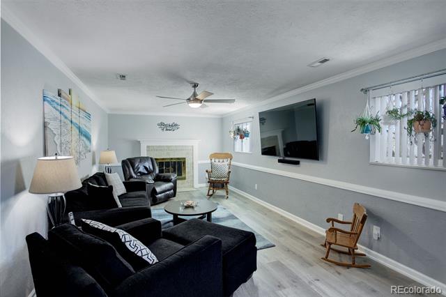 Living room with a black sectional, fireplace, wall-mounted television, and light wood flooring.