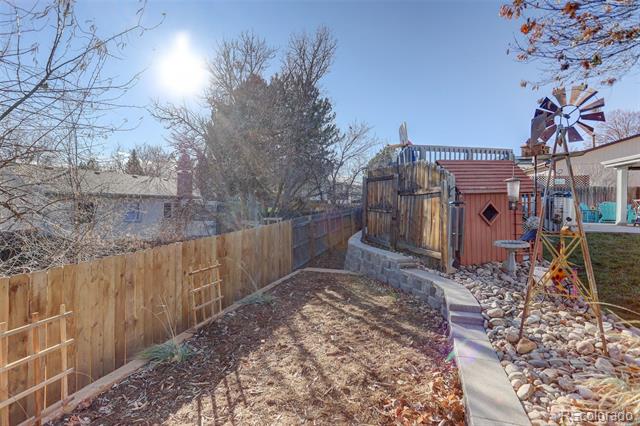 Backyard with a red shed, decorative windmill, wooden fence, and rock garden.