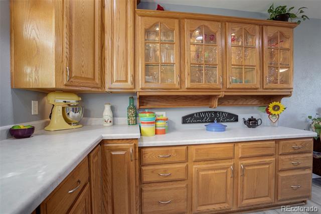 Kitchen with oak cabinetry, glass-front upper cabinets, and white countertops.