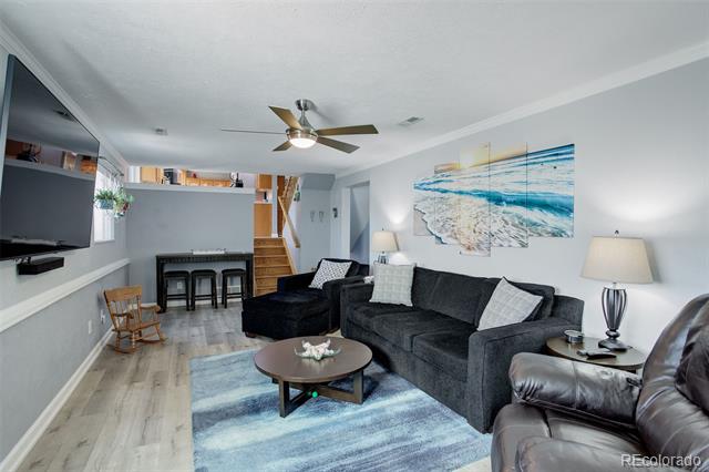 Living room with a dark sectional, blue rug, wall-mounted TV, and stairs.