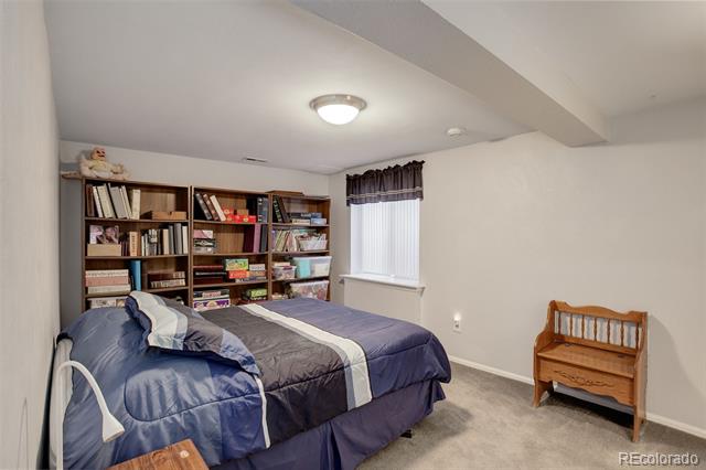 Bedroom with blue-and-gray bedding and bookshelves filled with books and board games.
