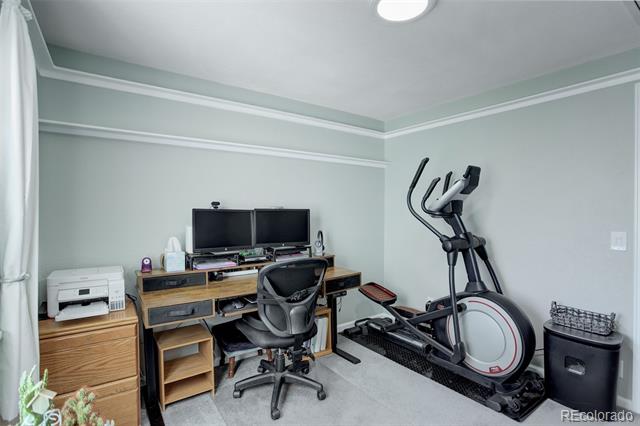 Home office with a dual-monitor desk, office chair, printer, and elliptical machine.