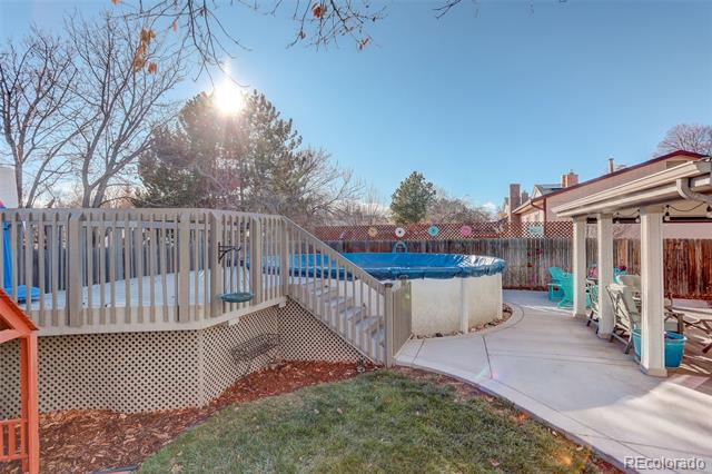 Backyard patio with a raised circular pool, wooden deck, and pergola-covered seating area.