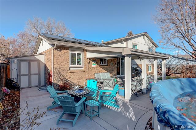 House’s rear patio with turquoise Adirondack chairs, covered seating area, and hot tub.