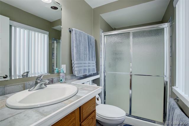 Bathroom with a wide vanity and oval sink beside frosted-glass sliding shower doors.