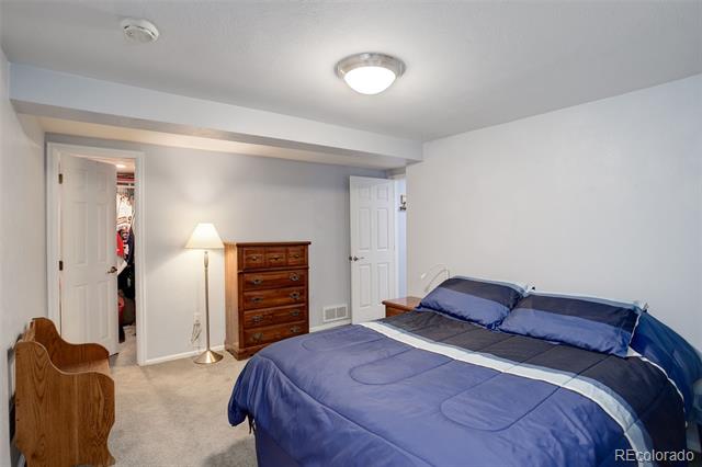 Bedroom with blue bedding, a wooden dresser, and a floor lamp.