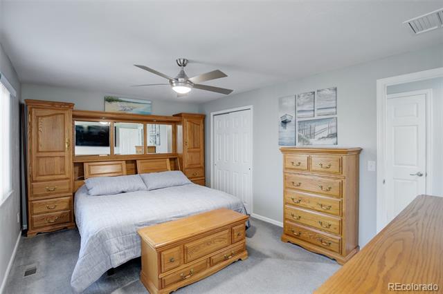 Bedroom with gray bedding, a wooden storage headboard, matching dresser, and chest at the foot of the bed.