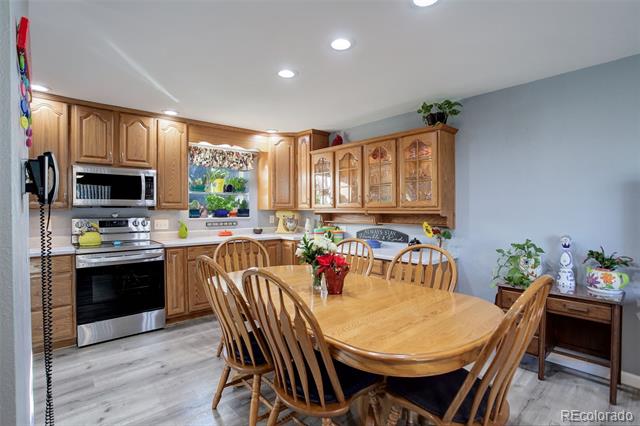 Kitchen and dining area with honey-colored cabinets, stainless appliances, and a large oval wooden table.